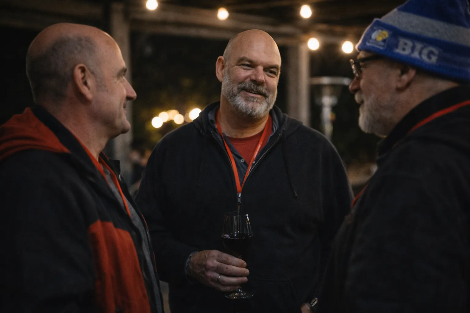 Three men laughing and talking over drinks in the evening at The Gathering
