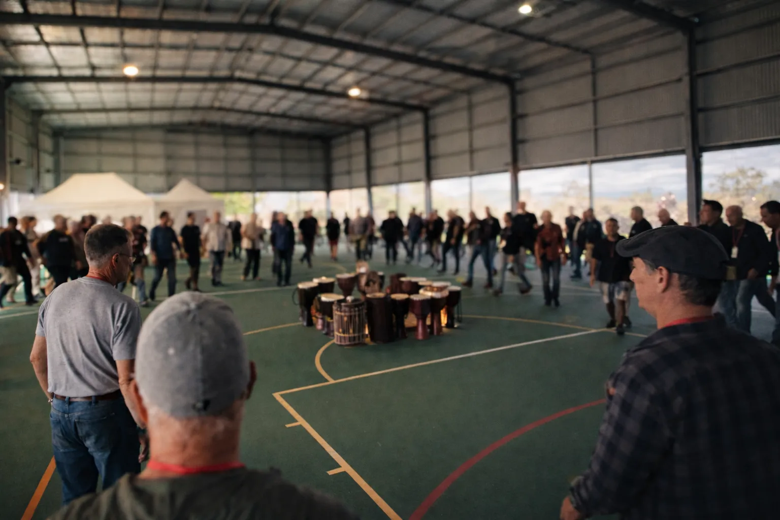Large group of men standing in a circle during an activity in a hall at The Gathering