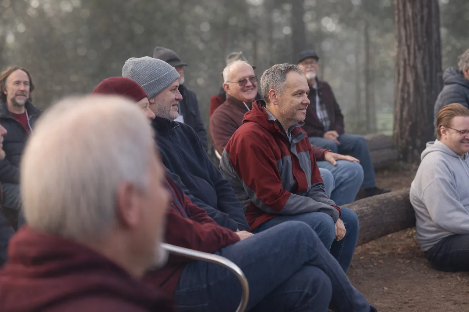 Men smiling and relaxed, sitting together in bushland during the rites of passage