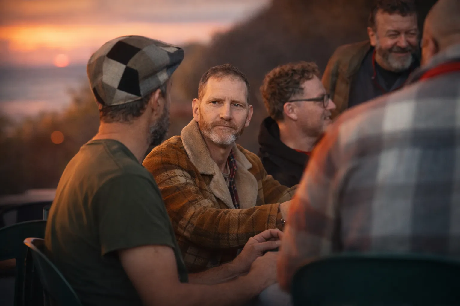 Men talking together around a table at sunset